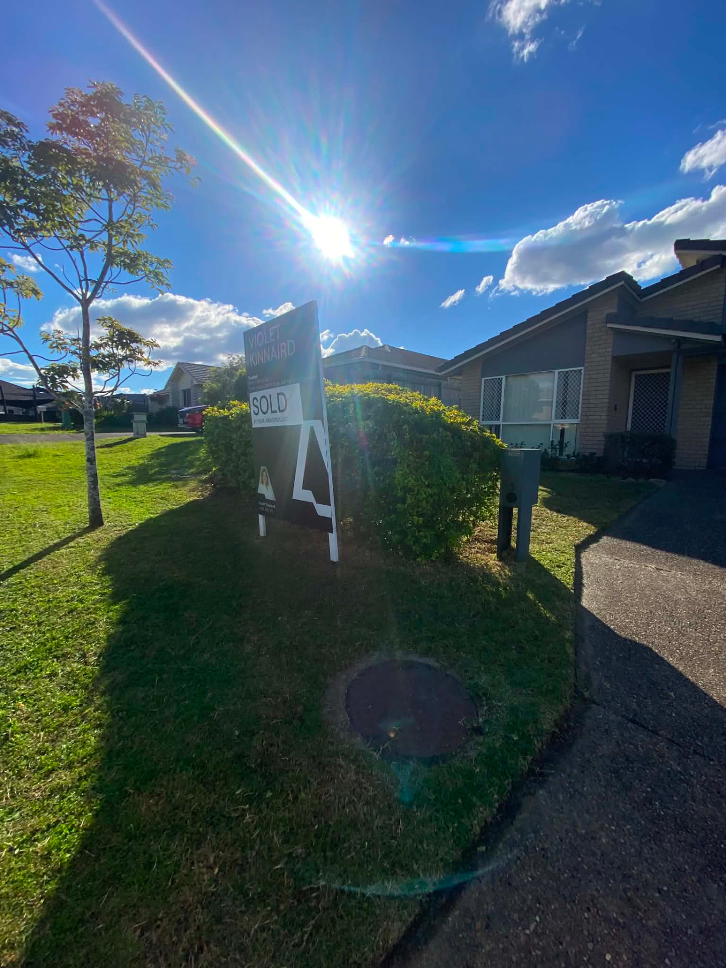 Corner block lawn mown around a hedge and street sign
