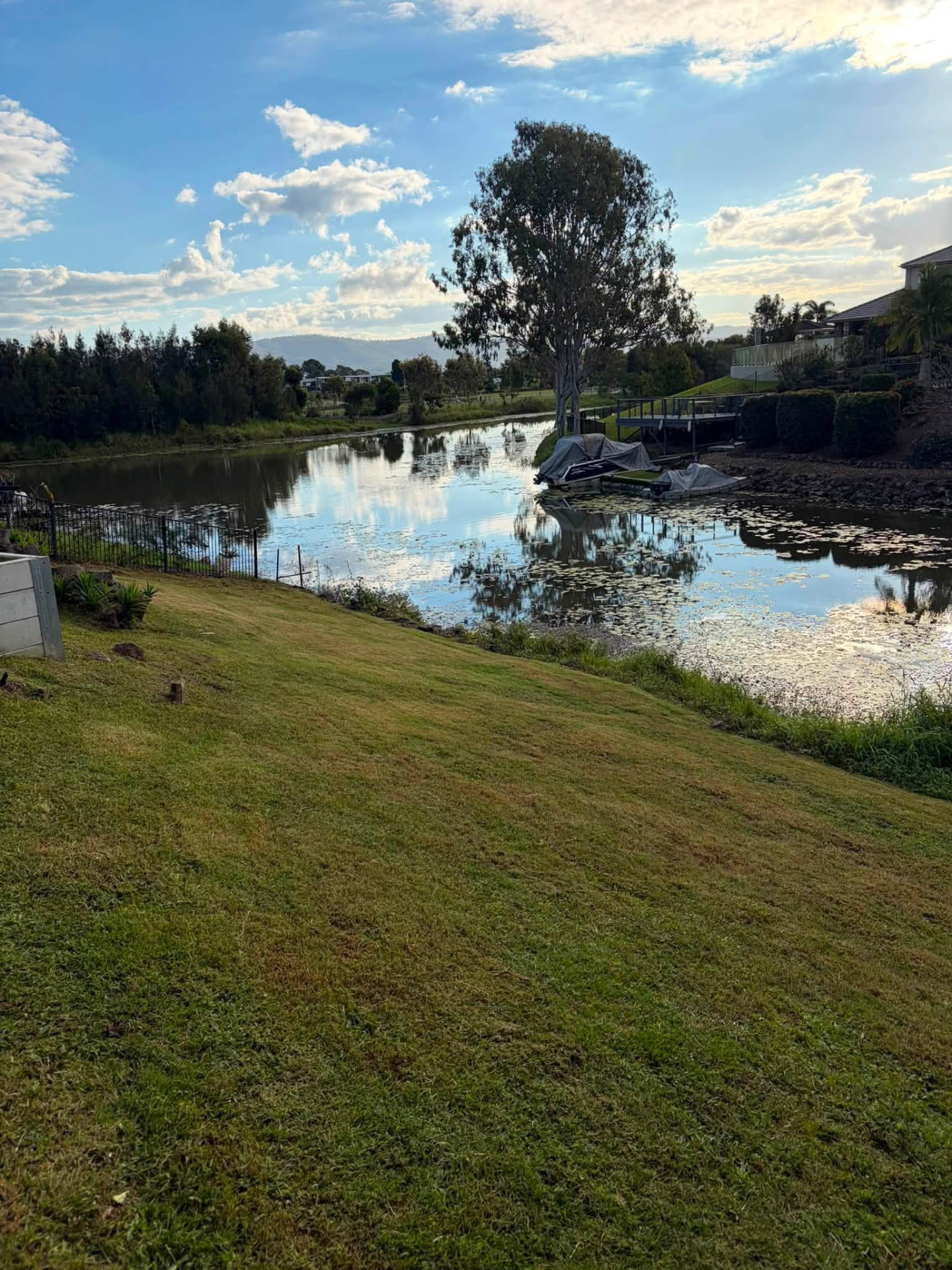 Wide waterfront lawn with a covered boat dock and mountain backdrop