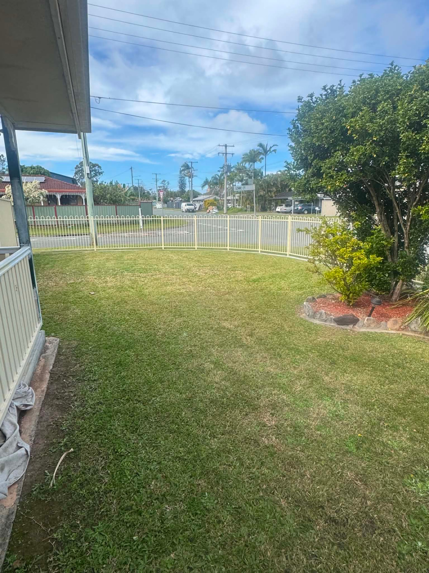 Neatly mown front lawn behind a white picket fence on the Gold Coast